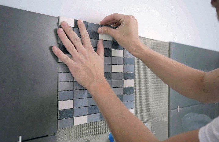 Eine Mosaikmatte wird an die Wand geklebt.