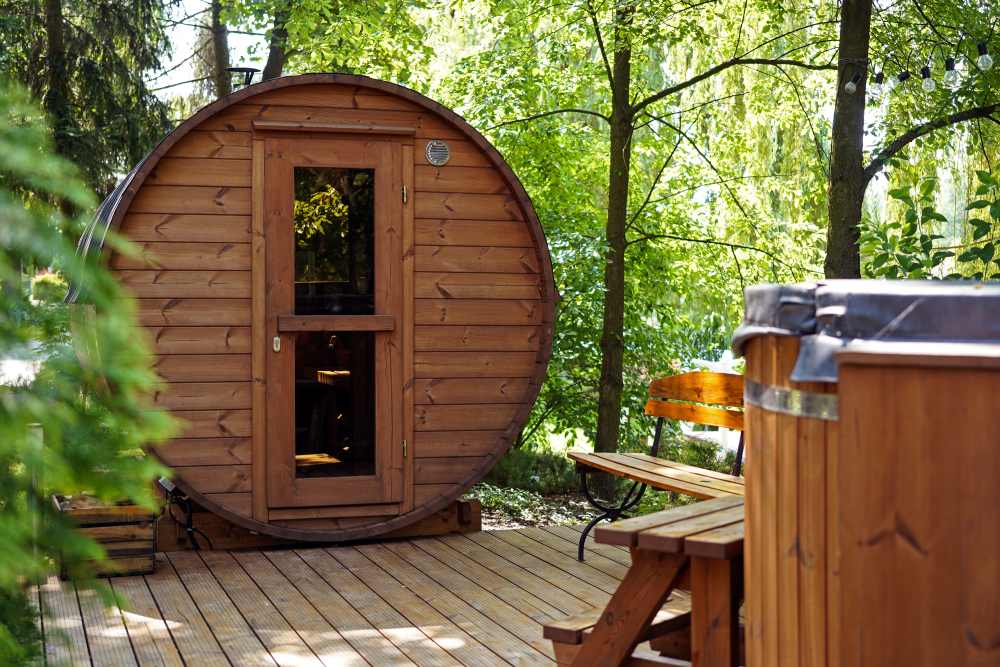 Eine Fasssauna aus Holz auf einer Terrasse im Garten.