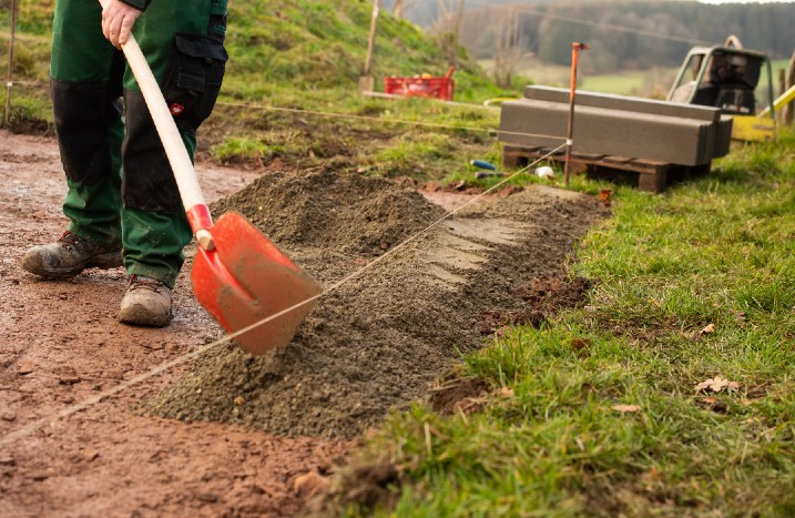 Eine Kiesschicht wird für ein Fundament auf dem Boden verteilt.
