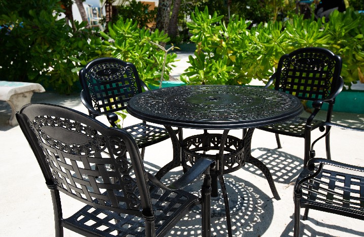 Schwarze Gartenstühle mit Tisch aus Metall auf Terrasse.
