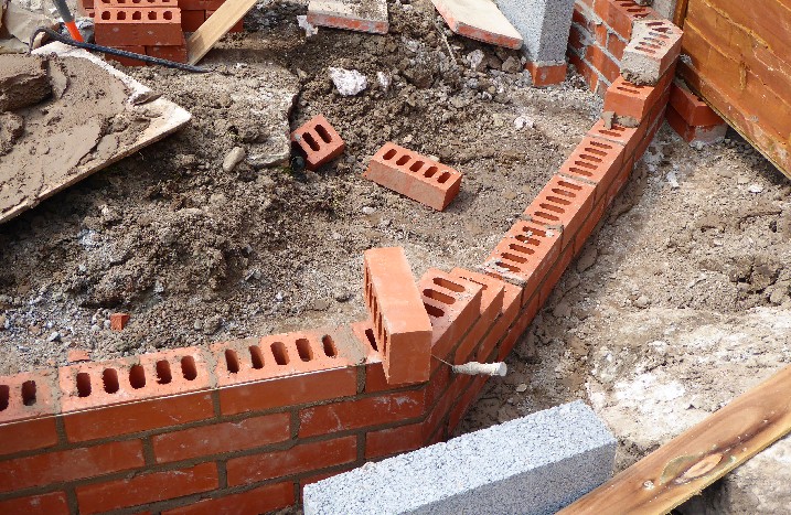 Im Garten wird mit Steinen das Fundament für ein Gewächshaus gelegt.