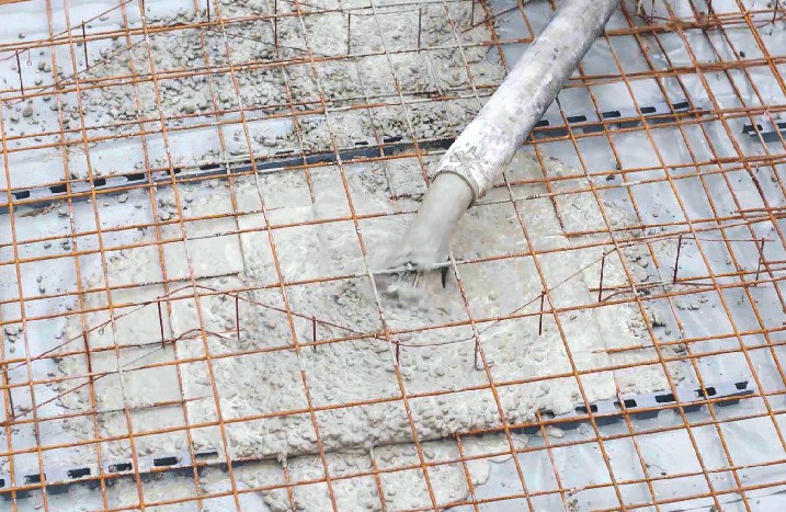 Mit einem Schlauch wird Beton auf die Drahtgitter gegossen.