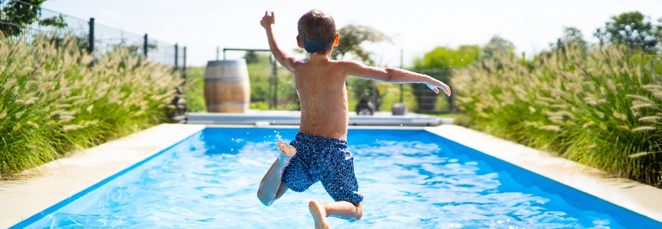 Ein Junge springt in einen Pool.