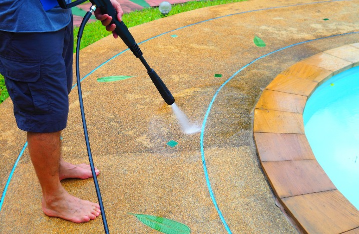 Mann reinigt Pool mit Hochdruckreiniger