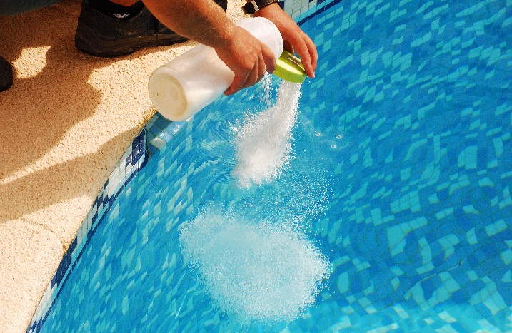 Granulat zum Anpassen des pH-Wertes wird in Pool geschüttet