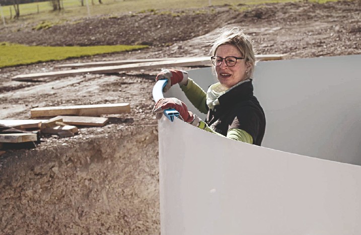 Handwerkerin stellt einen Stahlwandpool auf.
