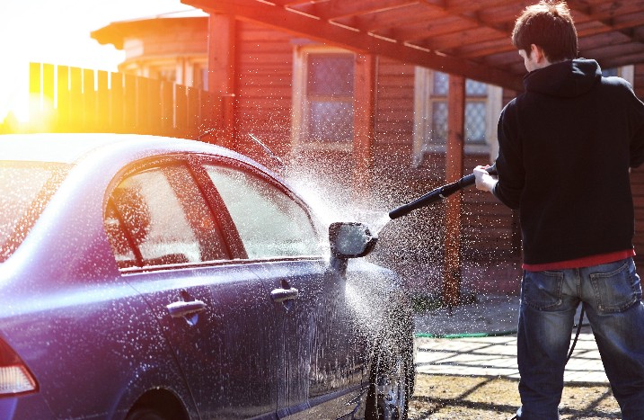 Ein Mann wäscht sein Auto vor dem Haus
