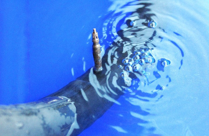 Ein Fahrradschlauch in einem Eimer voll Wasser, um defekte Stelle zu finden.