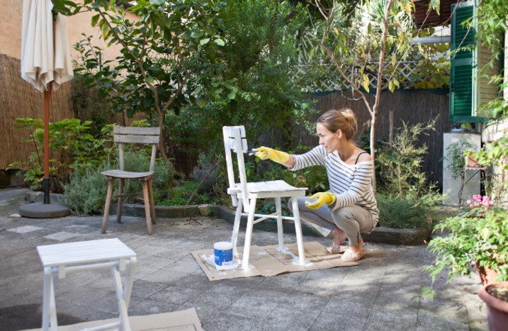 Frau lackiert Stuhl in Garten