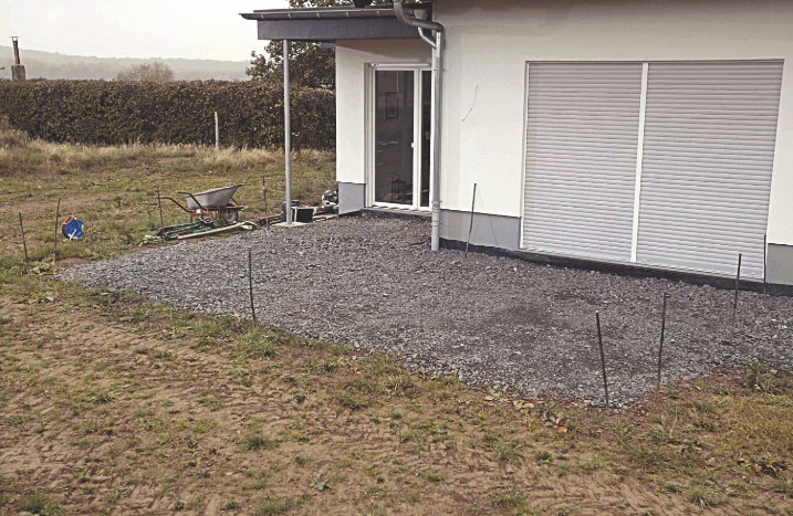 Der vorbereitete Untergrund für eine Holzterrasse in einem Garten.