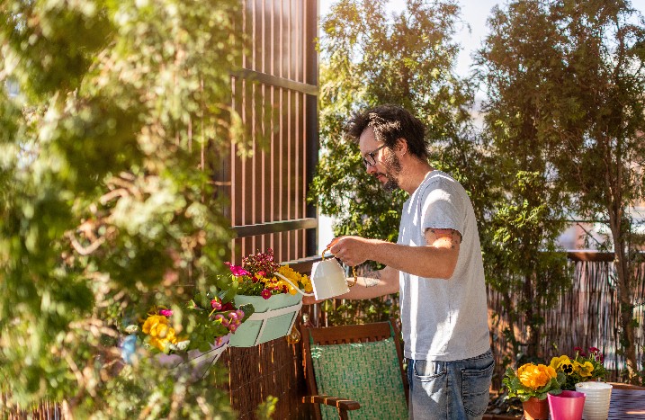 Mann gießt Pflanzen auf der Dachterrasse