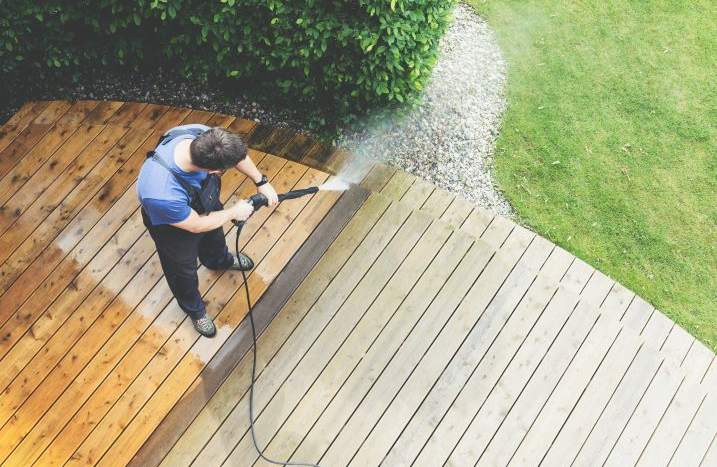Mann reinigt Terrasse mit Hochdruckreiniger