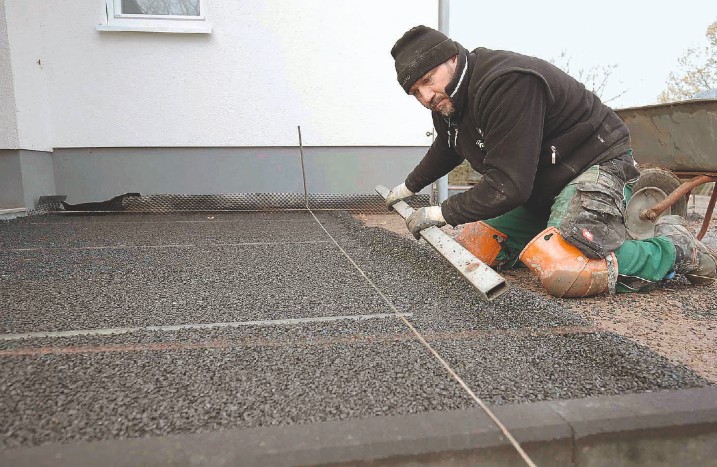 Ein Handwerker zieht ein Splittbett ab.