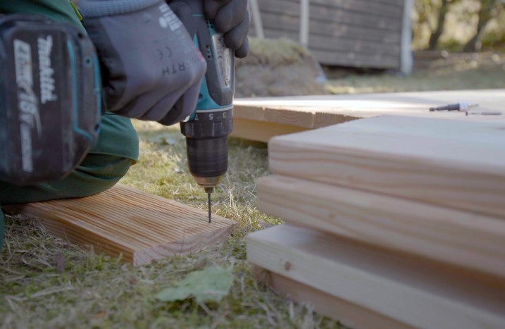 Ein Handwerke bohrt Löcher in Holzleisten vor.