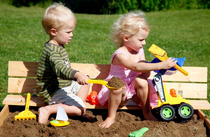 Kinder sitzen auf Sandkasten