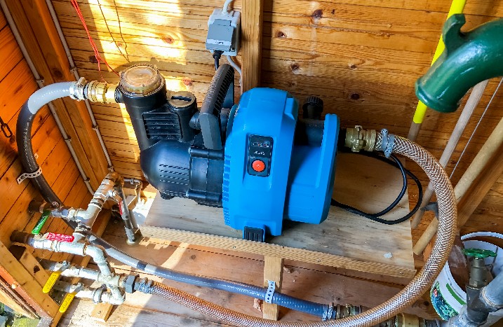 Eine Gartenpumpe umgeben von diversen Rohren im Gartenhäuschen.