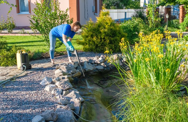Frau reinigt Teich