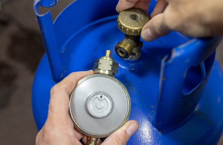 Nahaufnahme einer Gasflasche die an ein Ventil angeschlossen wird.