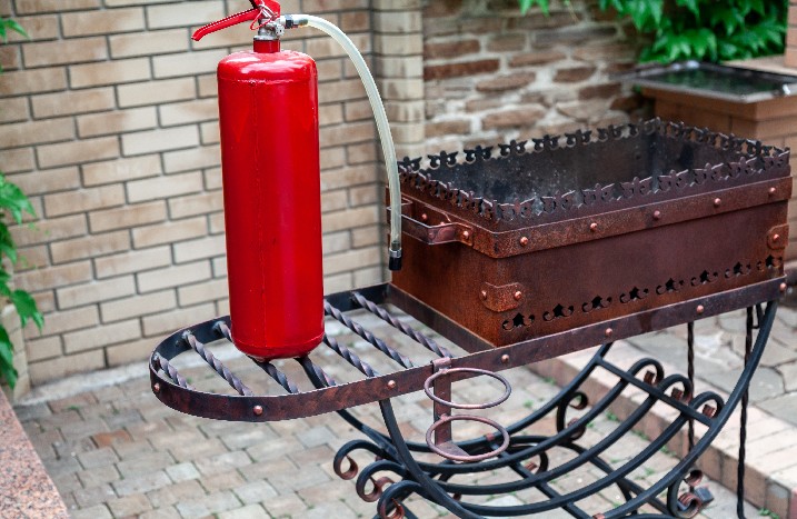 Ein Feuerlöscher neben einem alten Grill.