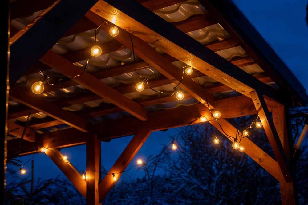 Eine Lichterkette beleuchtet einen Holzunterstand bei Nacht.