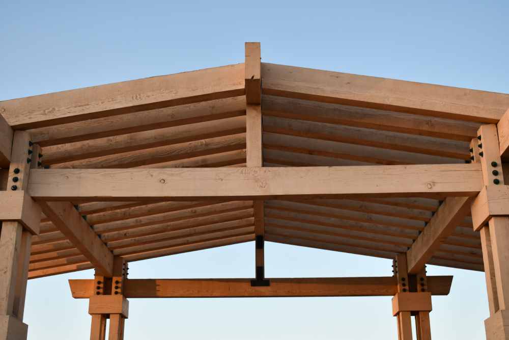 Nahaufnahme einer Dachkonstruktion aus Holz vor blauem Himmel.