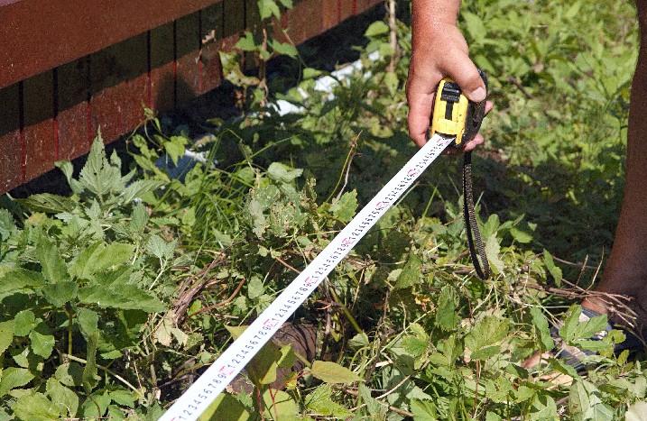 Im Garten wird mit dem Maßband etwas ausgemessen.