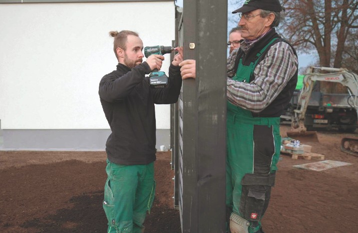 Handwerker befestigen gemeinsam einen Zaun aus Holz.