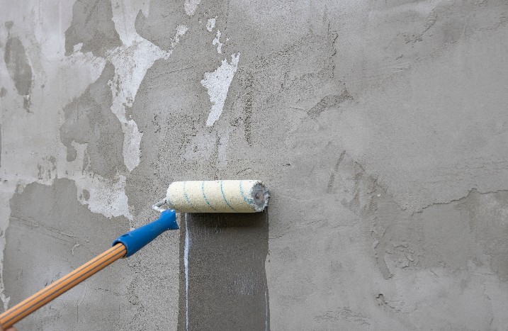 Betonwand grundieren Farbrolle streicht über Wand