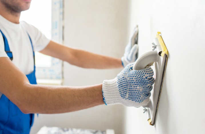 Untergrund vorbereiten Mann streicht über Wand Spachtel