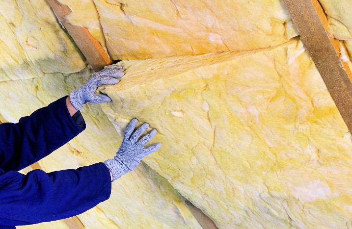 Handwerker bringt Dämmung an Wand an