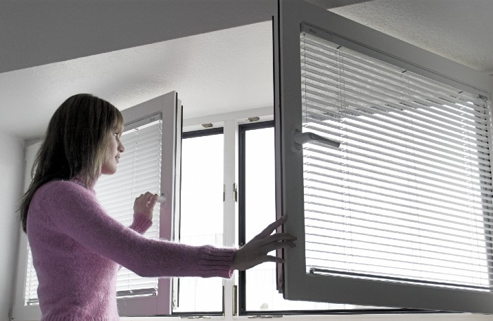 Frau öffnet Fenster weit