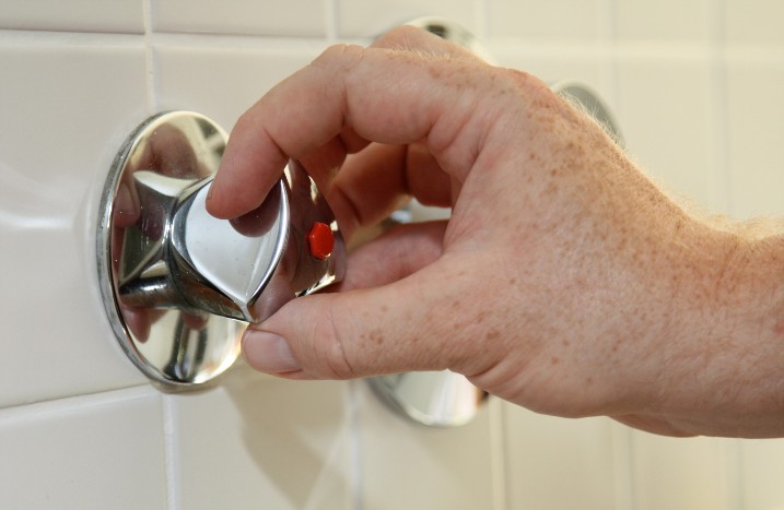 Hand dreht Wasserhahn zu
