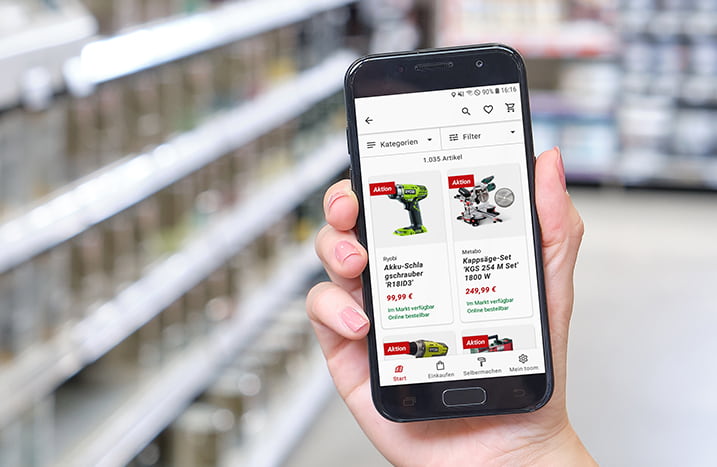 Handy vor Regalwand mit Angeboten