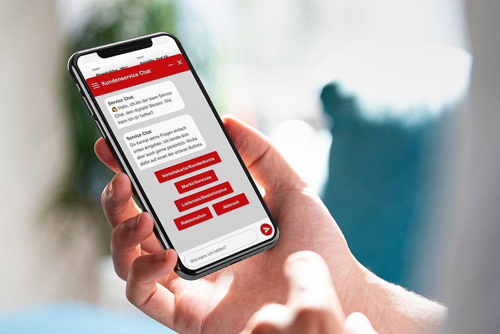 Person hält Smartphone mit geöffnetem Chatbot in der Hand