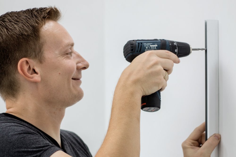 Person bringt mit Akkuschrauber Leiste an