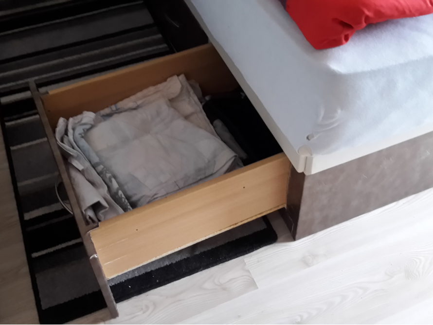 Offene Schublade unter einem Bett