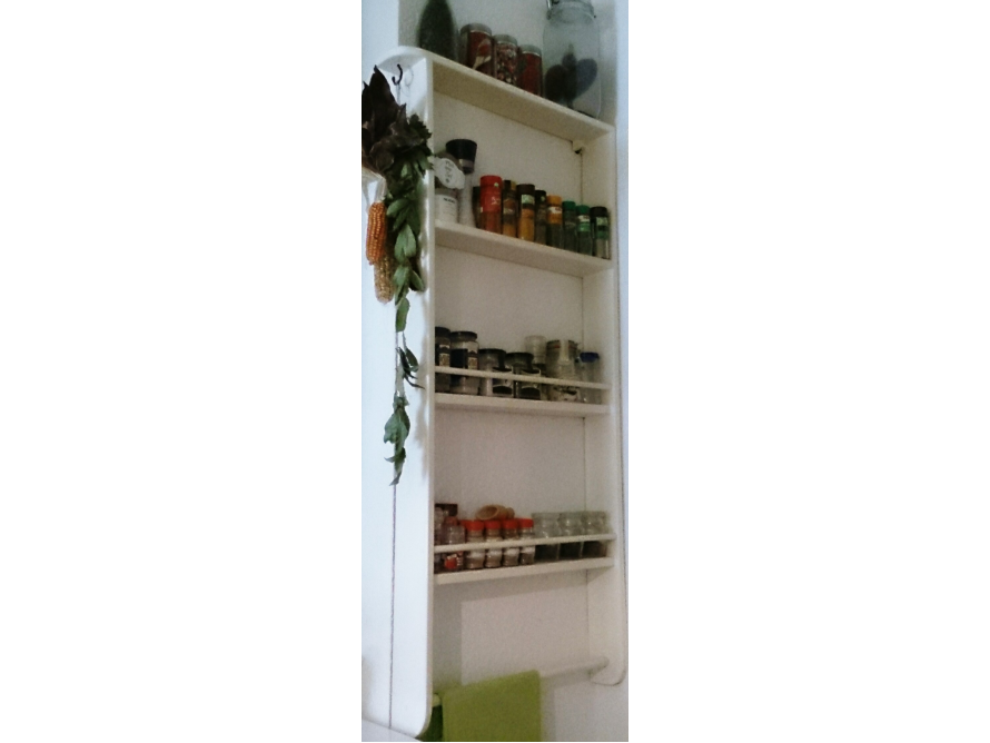 Weißes Gewürzregal mit Gewürzen