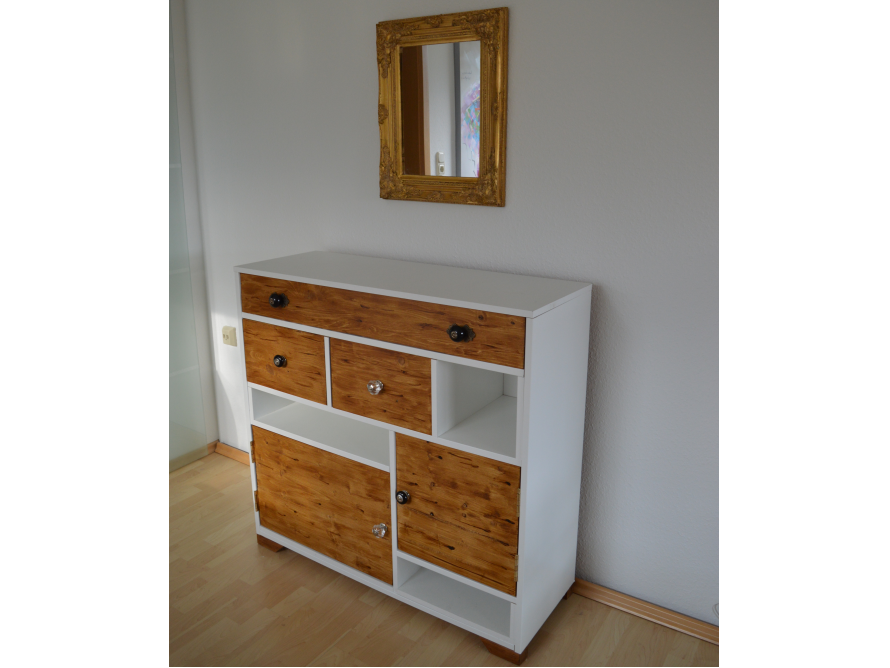 Ein weißer Schrank mit Schubladen und Türen aus hellem Holz.