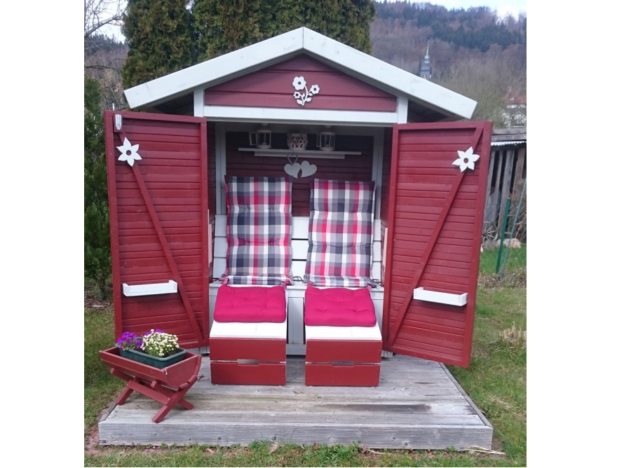 Rot gestrichenes Gartenhaus mit Sitzgelegenheit