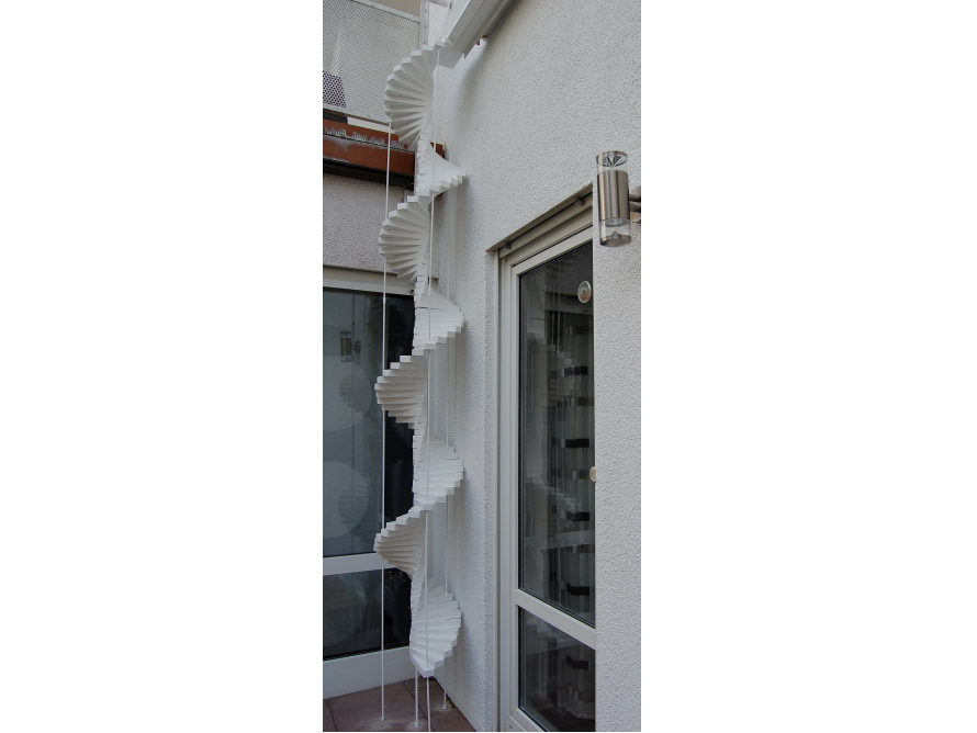 Eine weiße Wendeltreppe an einer Hauswand.