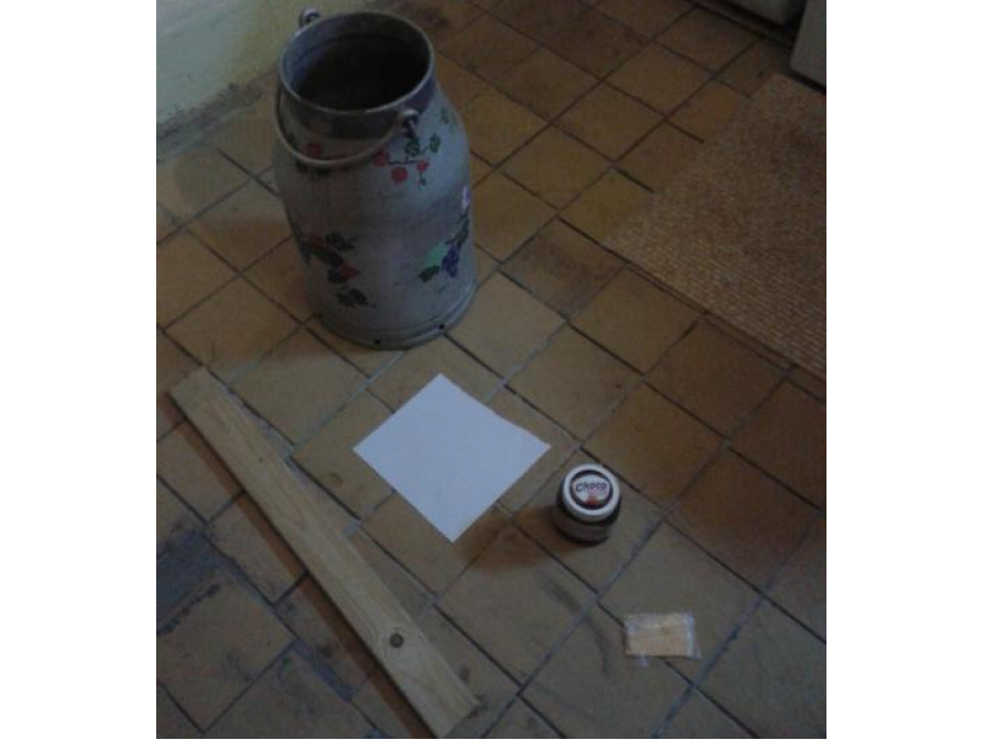 Holzlatte, Milchkrug und Dose auf Fliesenboden