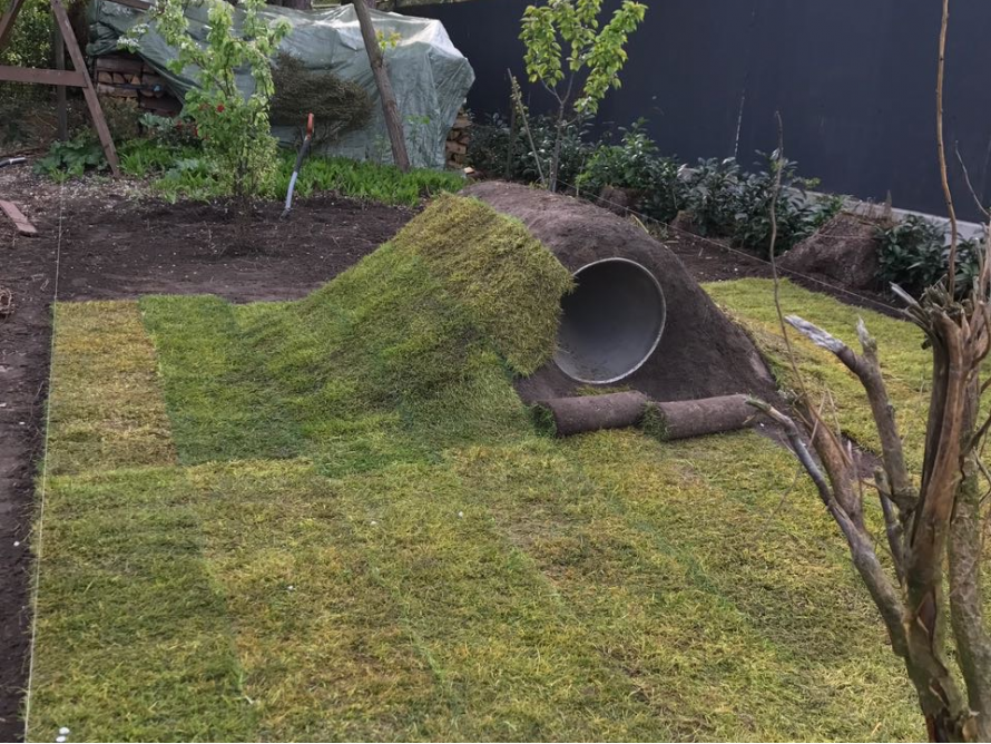 Rasen mit Erdhügel und Rohr