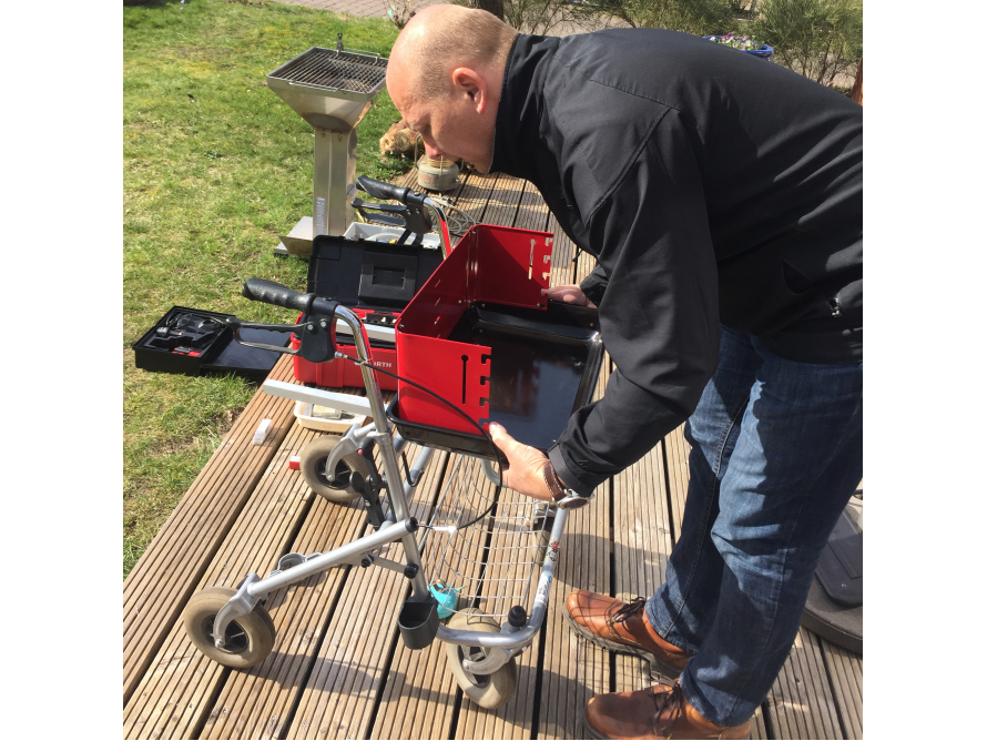Person baut einen Grill auf einer Holzterrasse zusammen