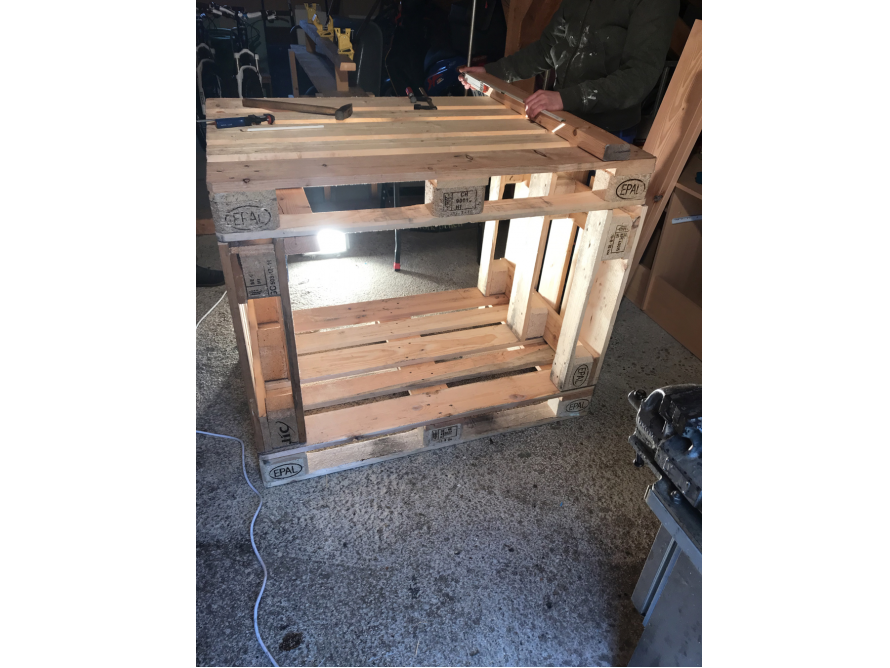 Person baut Möbelstück aus Paletten