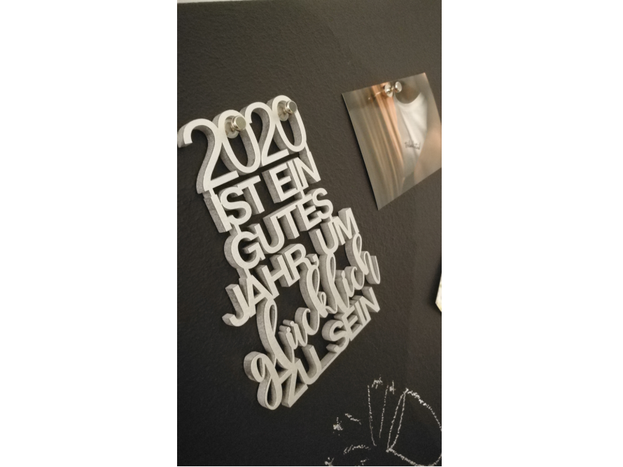 Silberfarbener Schriftzug "2020 ist ein gutes Jahr um glücklich zu sein" an schwarzer Pinnwand