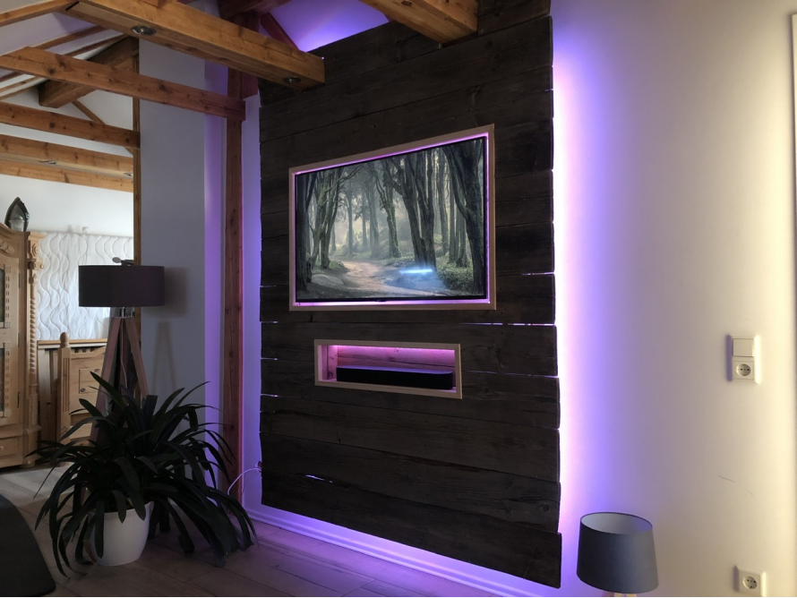 Fernseher an einer dunklen Holzwand mit lila Beleuchtung