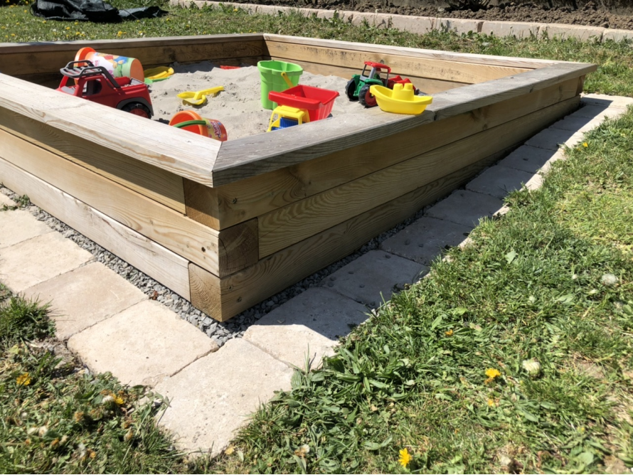 Ein Sandkasten aus Holz mit Spielzeug darin