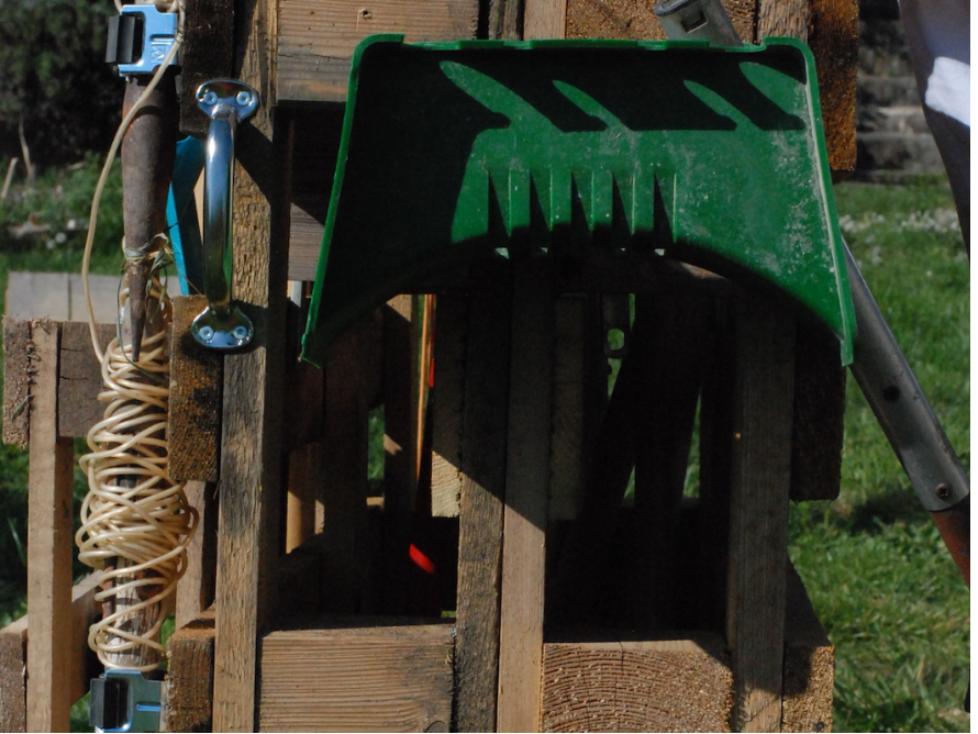 Gartenrechen und Gartenschere an Holzgestell