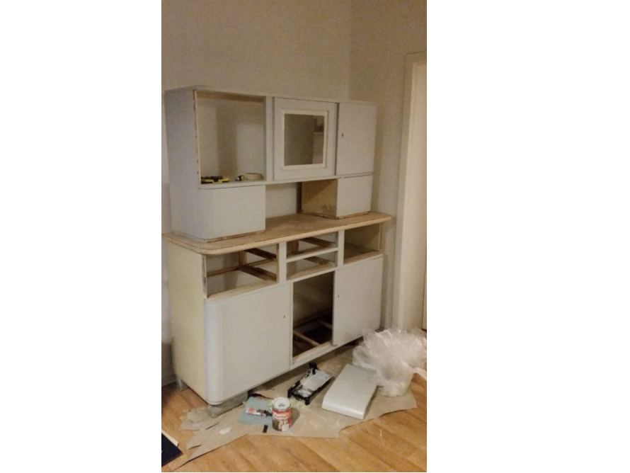 Ein halbfertiger Küchenschrank wird lackiert.