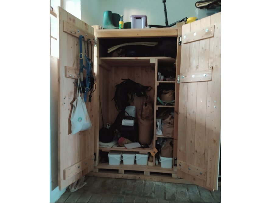 Offener Holzschrank mit Reitausrüstung